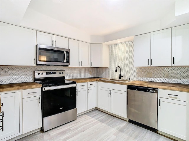 kitchen featuring white cabinets, butcher block counters, and stainless steel appliances