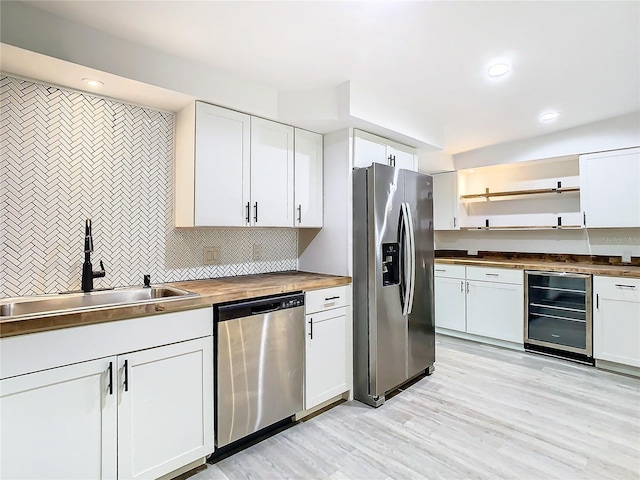 kitchen featuring butcher block counters, white cabinetry, sink, stainless steel appliances, and beverage cooler