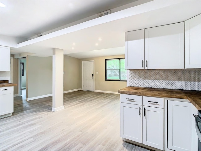 kitchen with white cabinets, decorative backsplash, and butcher block countertops