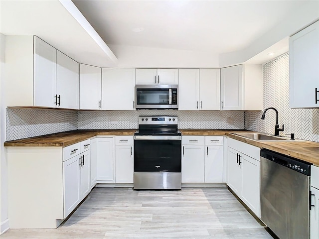 kitchen featuring sink, white cabinetry, butcher block counters, and appliances with stainless steel finishes