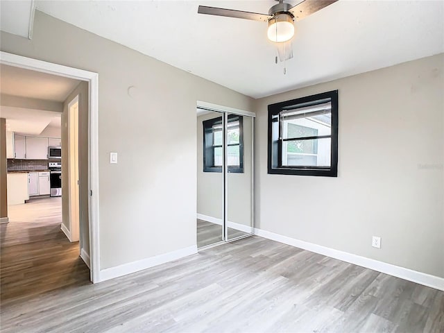 unfurnished bedroom featuring ceiling fan, a closet, and light hardwood / wood-style flooring