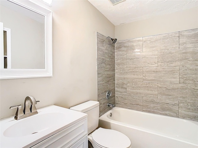 full bathroom with tiled shower / bath combo, toilet, a textured ceiling, and vanity