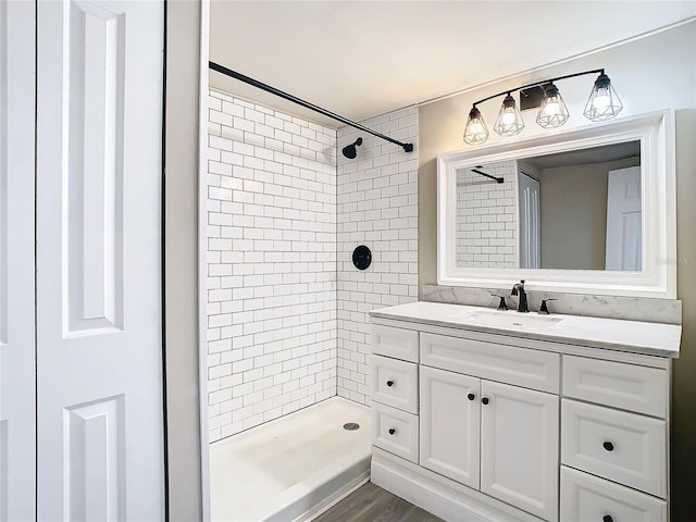 bathroom featuring wood-type flooring, vanity, and a tile shower