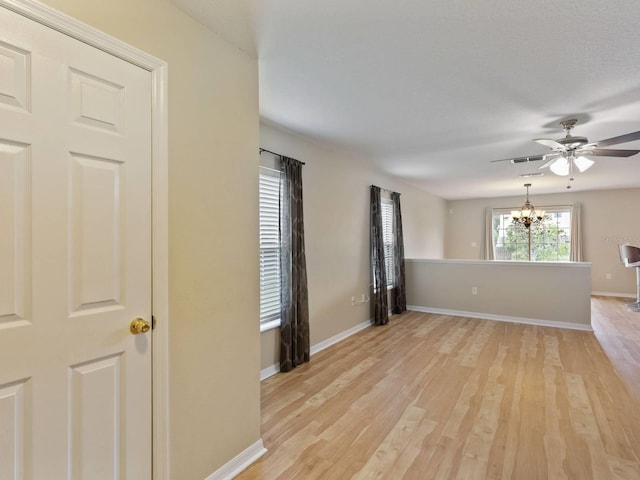 spare room featuring ceiling fan with notable chandelier and light hardwood / wood-style flooring