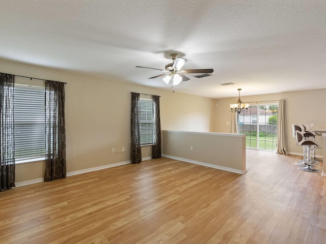 unfurnished room featuring ceiling fan with notable chandelier, a textured ceiling, and light hardwood / wood-style floors