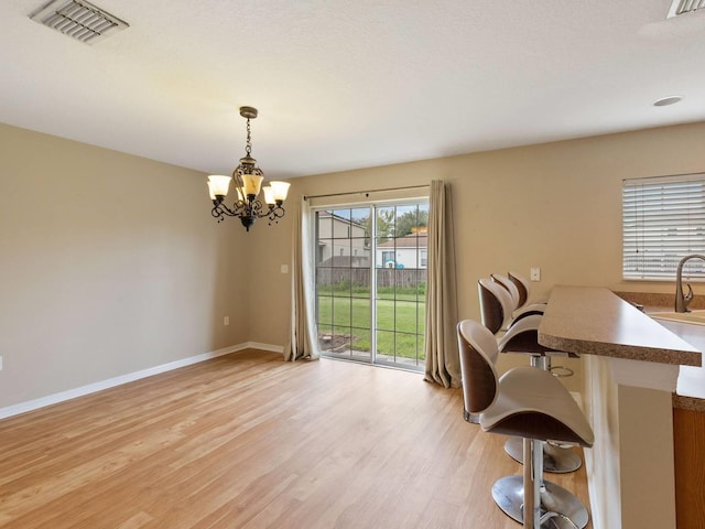 unfurnished dining area featuring an inviting chandelier, light hardwood / wood-style floors, and a textured ceiling