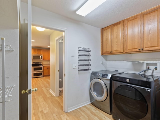 laundry area featuring independent washer and dryer, light hardwood / wood-style floors, cabinets, and a textured ceiling