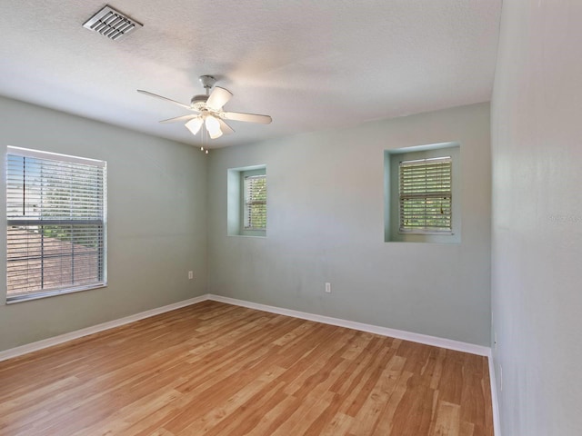 empty room with a textured ceiling, light hardwood / wood-style flooring, and ceiling fan