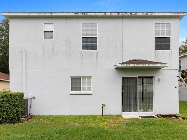 back of property featuring a lawn and central air condition unit