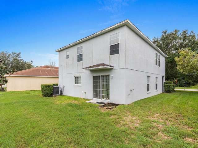 back of house featuring central air condition unit and a lawn