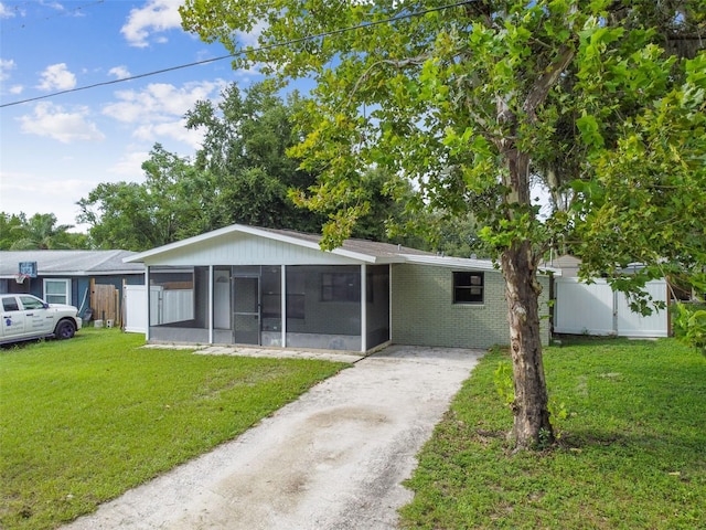 single story home featuring driveway, fence, a front yard, and a sunroom