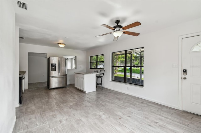 kitchen with stainless steel fridge with ice dispenser, light hardwood / wood-style flooring, white cabinets, and ceiling fan