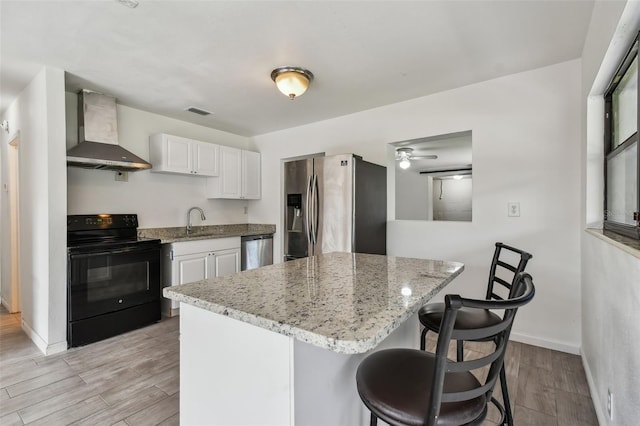 kitchen featuring white cabinets, sink, wall chimney exhaust hood, light hardwood / wood-style floors, and stainless steel appliances