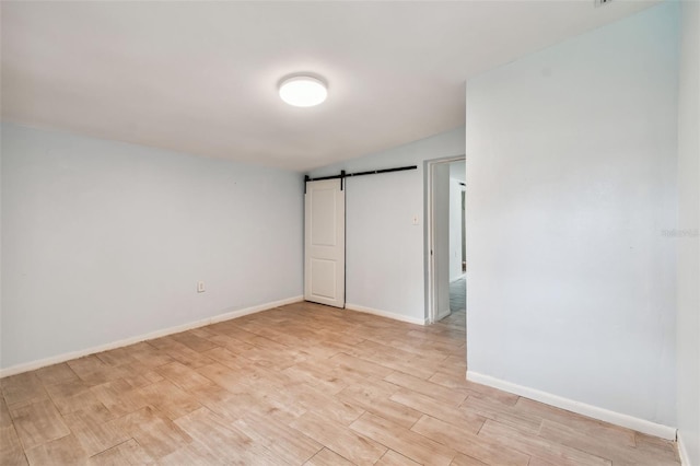 unfurnished bedroom featuring a barn door and light wood-type flooring