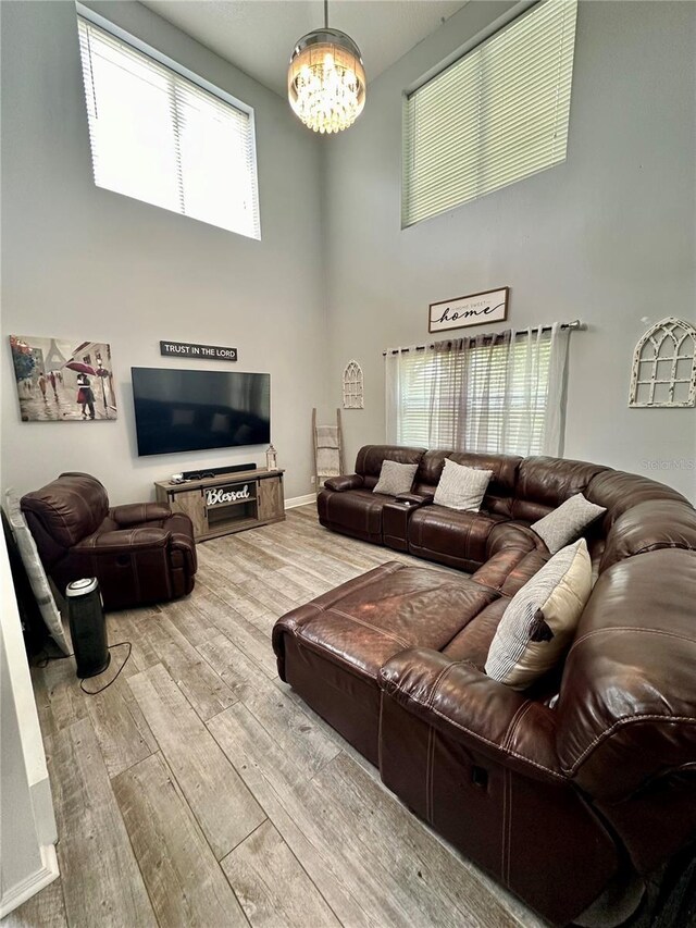 living room with a high ceiling, hardwood / wood-style floors, and an inviting chandelier