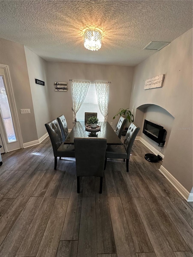 dining room with dark wood-type flooring and a textured ceiling