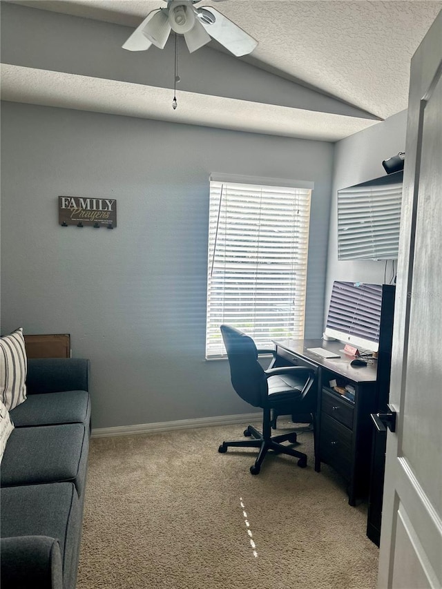 carpeted office featuring ceiling fan, a healthy amount of sunlight, lofted ceiling, and a textured ceiling