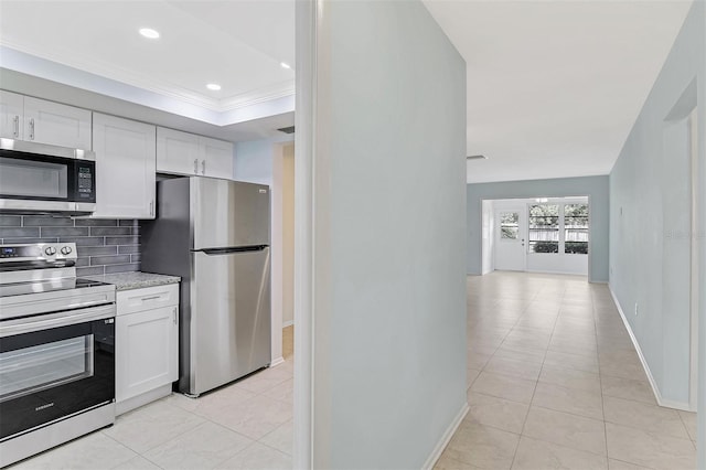 kitchen with decorative backsplash, ornamental molding, white cabinets, light tile patterned floors, and stainless steel appliances