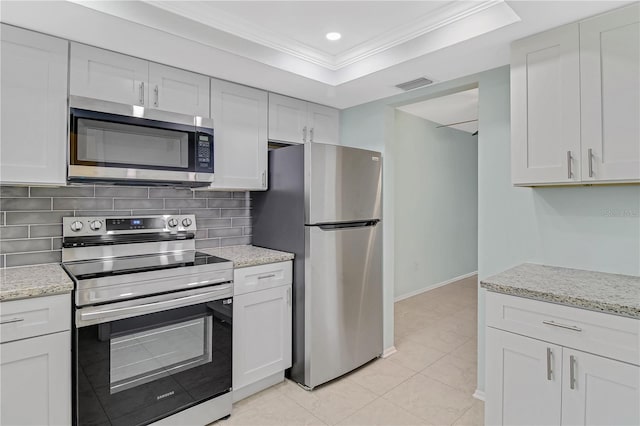 kitchen featuring tasteful backsplash, a tray ceiling, white cabinets, appliances with stainless steel finishes, and crown molding