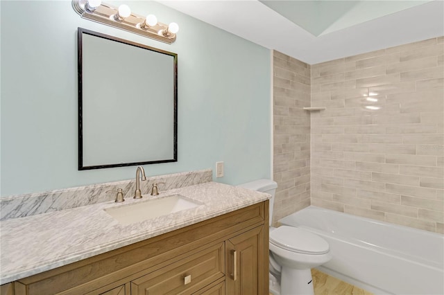 full bathroom with hardwood / wood-style floors, tiled shower / bath, toilet, and vanity