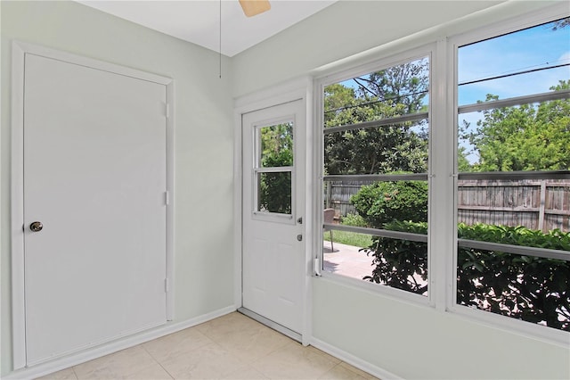 doorway to outside featuring light tile patterned floors, ceiling fan, and a healthy amount of sunlight