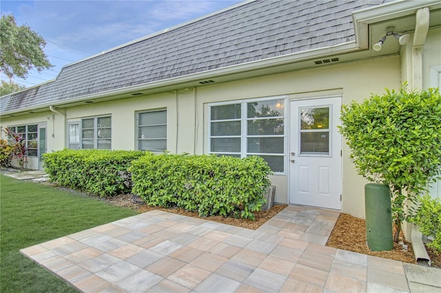 entrance to property featuring a patio area and a yard