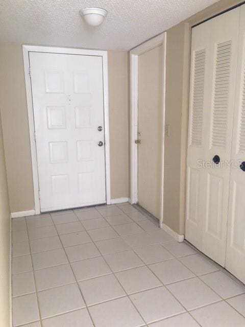 foyer entrance with light tile patterned floors and a textured ceiling