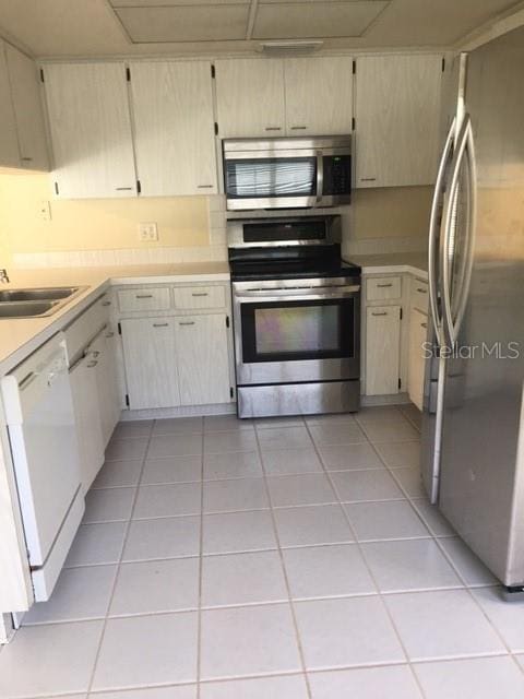 kitchen featuring light tile patterned floors, stainless steel appliances, light countertops, and a sink