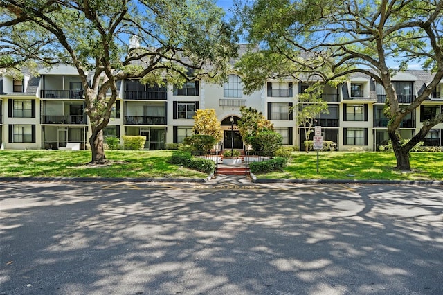 view of front of property with a balcony and a front lawn