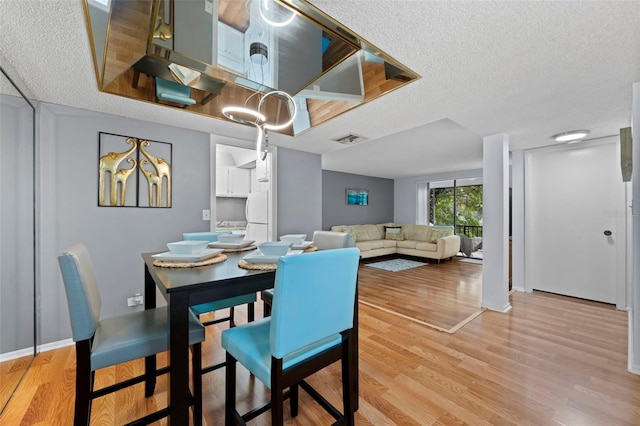 dining room featuring light wood-type flooring and a textured ceiling