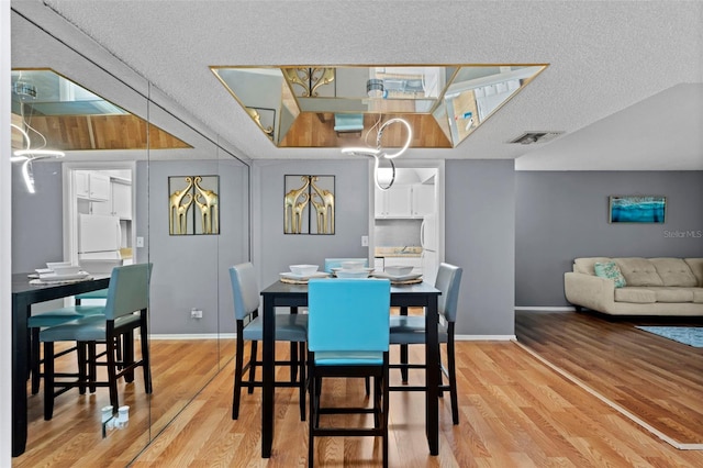 dining space with a textured ceiling and light hardwood / wood-style floors