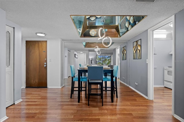 dining room with wood-type flooring and a textured ceiling