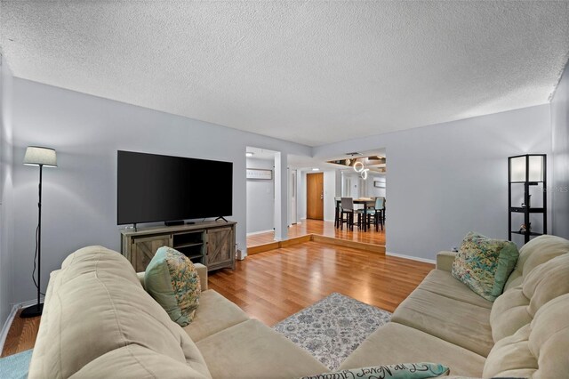 living room with a textured ceiling, ceiling fan, and hardwood / wood-style floors