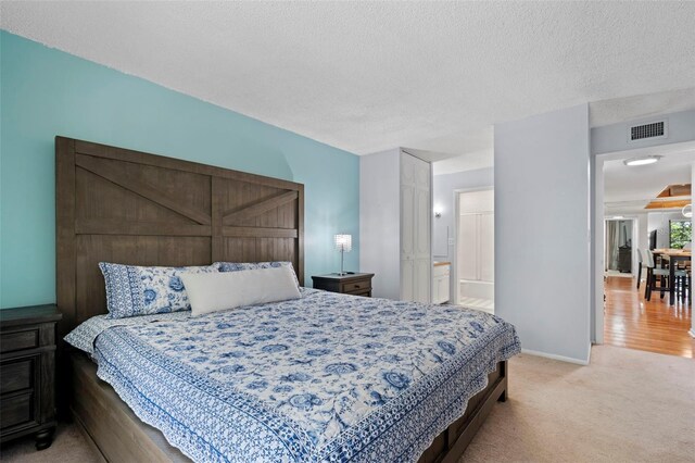 bedroom featuring carpet floors, a textured ceiling, and connected bathroom