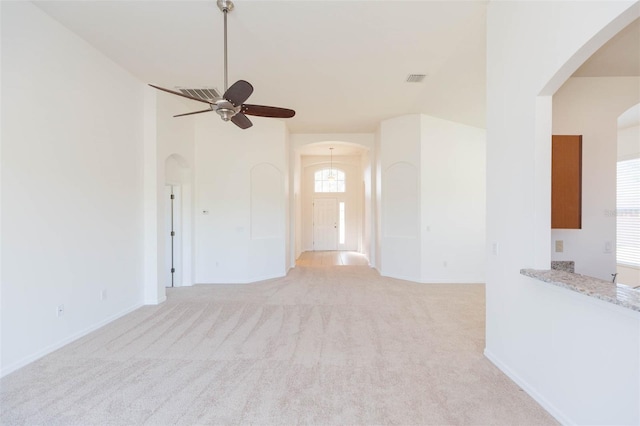 carpeted spare room featuring ceiling fan and a high ceiling