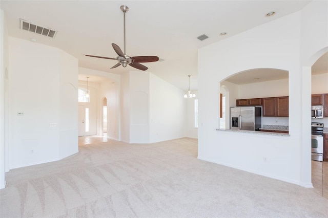 unfurnished living room with high vaulted ceiling, light colored carpet, and ceiling fan