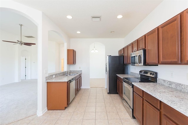 kitchen featuring sink, light stone counters, light carpet, appliances with stainless steel finishes, and ceiling fan with notable chandelier