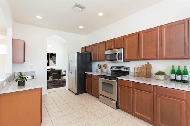 kitchen featuring stainless steel appliances, light tile patterned floors, and light stone counters