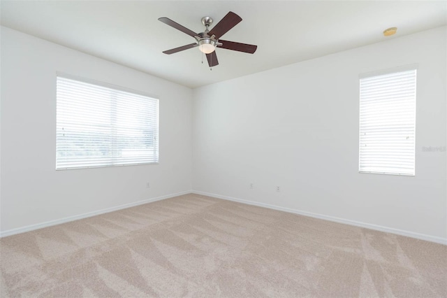 spare room with ceiling fan, light colored carpet, and a healthy amount of sunlight