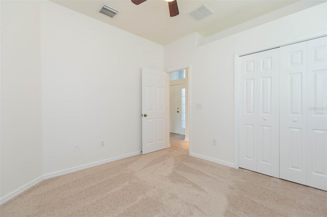 unfurnished bedroom with light colored carpet, a closet, and ceiling fan