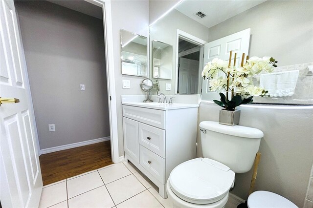 bathroom featuring tile patterned floors, toilet, vanity, baseboards, and visible vents