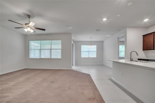 unfurnished living room with sink, ceiling fan, and light colored carpet