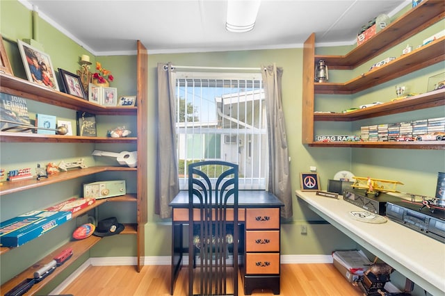 office featuring built in desk, light wood-type flooring, and ornamental molding