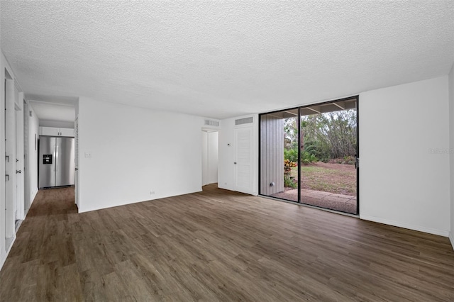 interior space with visible vents, dark wood finished floors, a textured ceiling, and a wall of windows