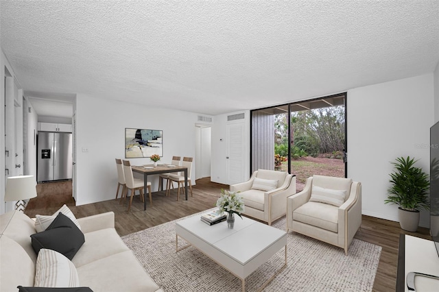 living room featuring visible vents, a textured ceiling, and wood finished floors