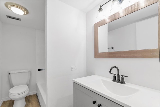 bathroom with toilet, wood finished floors, vanity, visible vents, and baseboards