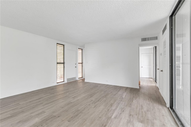 unfurnished room with light wood-style floors, visible vents, and a textured ceiling