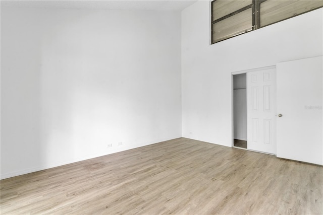 empty room featuring light wood-style floors and a towering ceiling