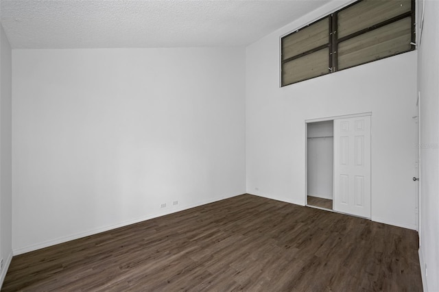 unfurnished bedroom featuring a textured ceiling, dark wood-type flooring, a closet, and baseboards