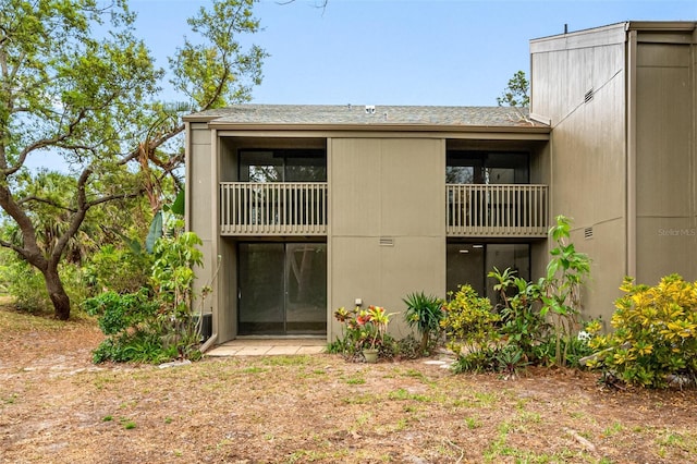 exterior space featuring a shingled roof and a balcony